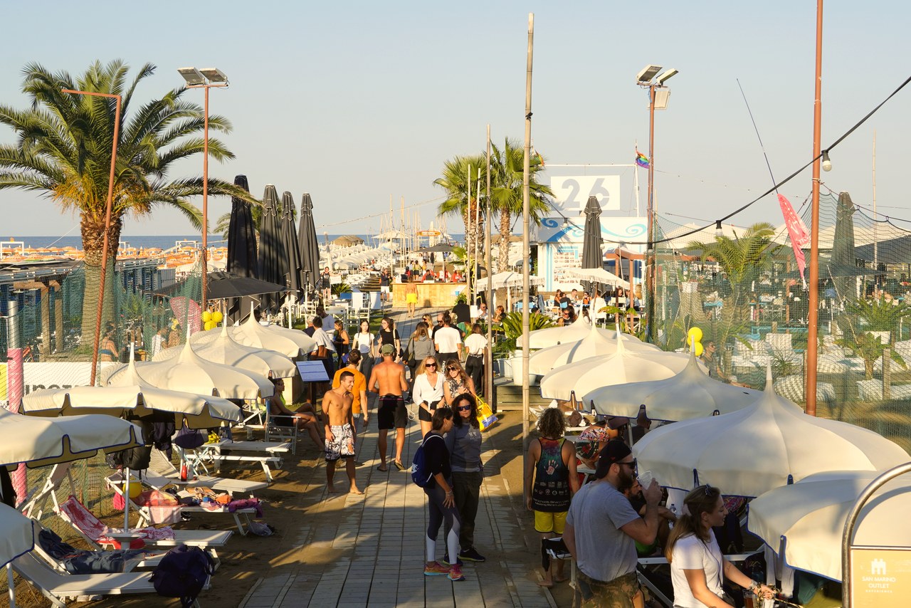 Beachvolleyball-Urlaub: entspannte Beach-Club-Promenade mit Liegestühlen und Palmen